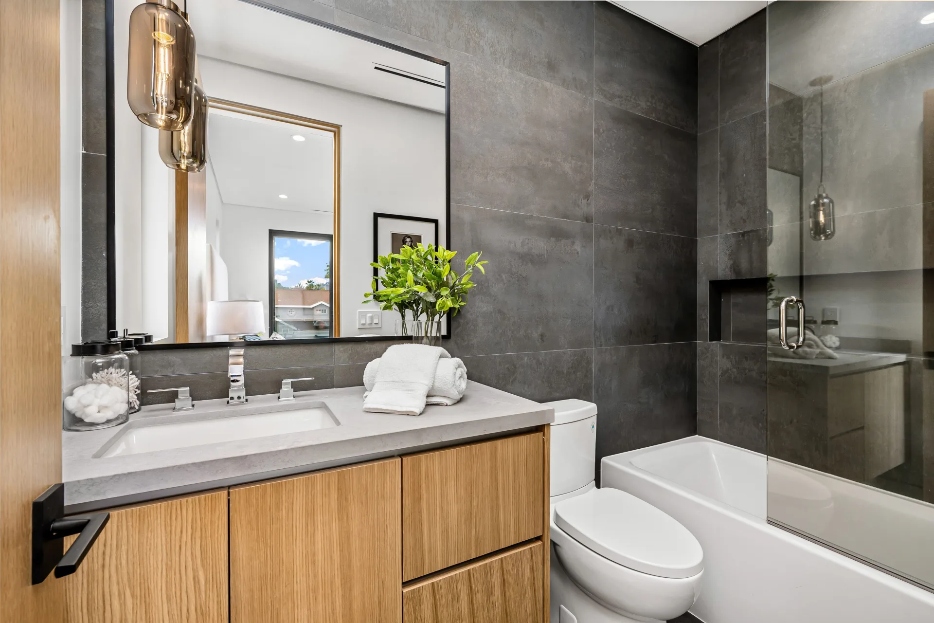 Modern bathroom with grey tile, an oak vanity and a glass shower