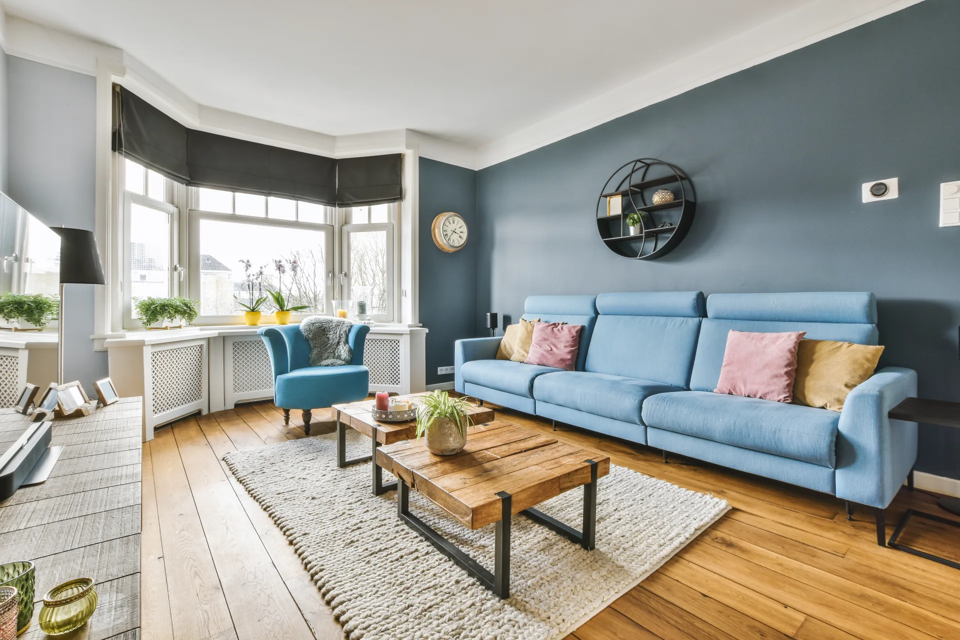 Living room with a blue sofa, a wooden coffee table and a bay window